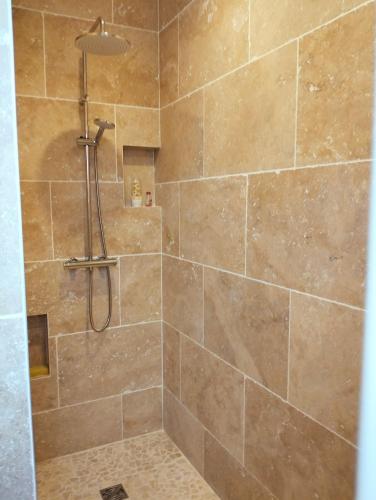 La salle de bains est pourvue d'une douche et d'un grand mur en pierre. dans l'établissement Maison l'Angelina, à Pinet