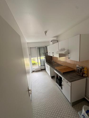 une cuisine avec des armoires blanches et un sol carrelé dans l'établissement Cosy flat all confort Puteaux, à Puteaux