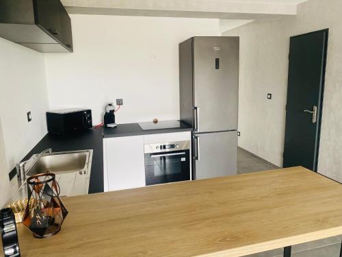 une cuisine avec un réfrigérateur en acier inoxydable et une table dans l'établissement Appartement en Camargue, à Aigues-Mortes