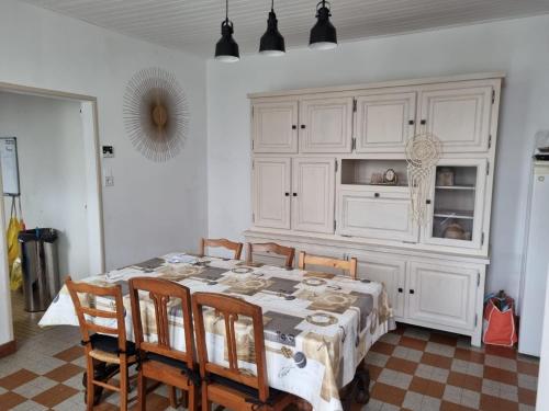 d'une table à manger avec des chaises et une armoire blanche. dans l'établissement Maison bord de mer, à La Faute-sur-Mer