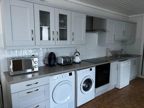 - une cuisine avec des placards blancs et un lave-linge/sèche-linge dans l'établissement Teach Róise, à Dunfanaghy