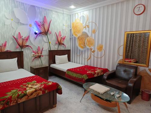 a hotel room with two beds and a chair at Al Madina Guest House in Hyderabad