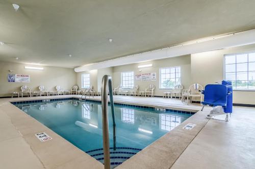 a swimming pool with chairs and a blue chair at Cobblestone Hotel & Suites - McCook in McCook