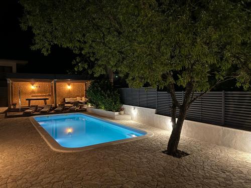 uma piscina com uma árvore num quintal à noite em Villa Antika em Velika Cista