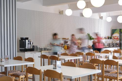 Menschen laufen in einem Restaurant mit Tischen und Stühlen herum in der Unterkunft Centrum Salvator in Bratislava