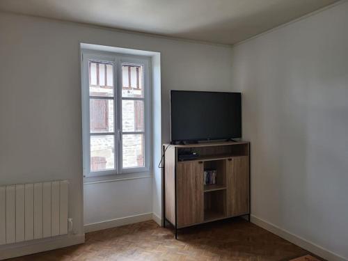 un salon avec une télévision à écran plat et une fenêtre dans l'établissement La libellule Pelaude Appartement 4-6 personnes avec terrasse, à Eymoutiers