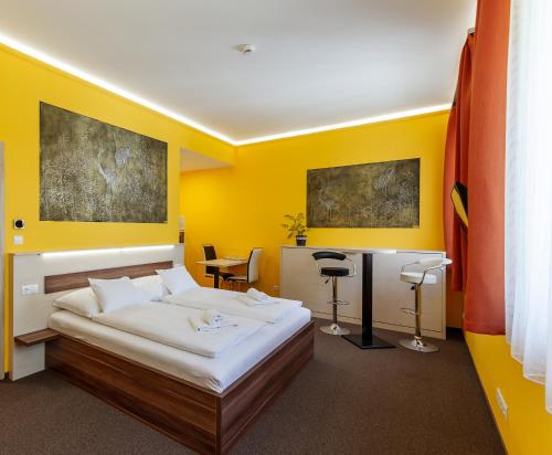 a yellow bedroom with a bed and a desk at Hostel Mayer Superior Veszprém in Veszprém