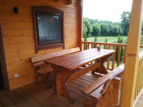 a wooden bench on the porch of a log cabin at Domki Blizniaki in Żywki
