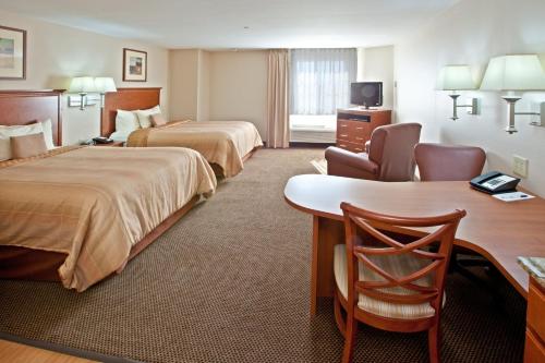 a hotel room with two beds and a desk at Candlewood Suites Lafayette, an IHG Hotel in Lafayette