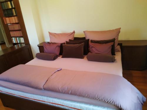 a large bed with pink and purple pillows on it at Aquincum Dunaparti Apartman in Budapest