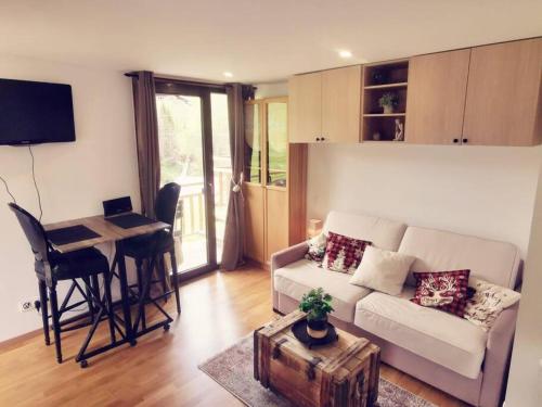 un salon avec un canapé et une table avec un ordinateur portable dans l'établissement Studio LE MONT, à Hauteluce