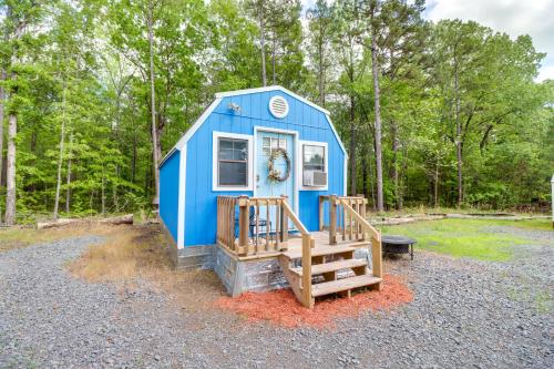 a blue tiny house with a porch and a staircase at Higden Studio with Shared Patio, Yard Games, Grills! in Fairfield Bay