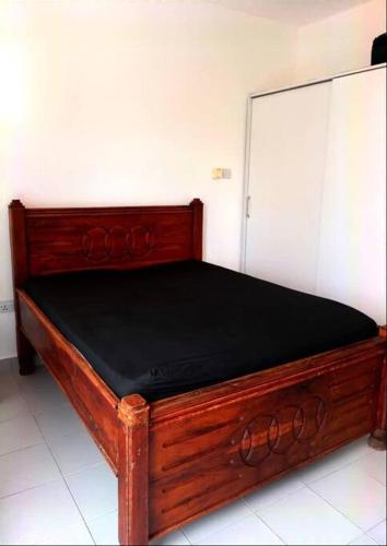 a wooden bed in a room with a black mattress at Escape the noise in Dambani