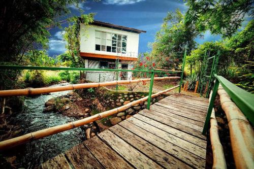 un puente de madera sobre un río con un edificio en el fondo en Rainforest Cabin in Escazu, en Escazú