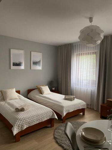 1 dormitorio con 2 camas, mesa y ventana en Willa Polanka en Gościno