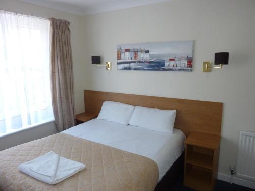 a bedroom with a bed with a white towel on it at Serenity Hotel in Bournemouth