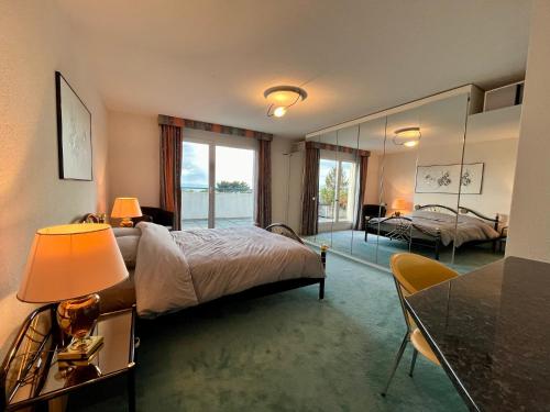 een slaapkamer met een bed en een tafel met een lamp bij Spacieux attique avec vue sur le lac in Saint-Blaise