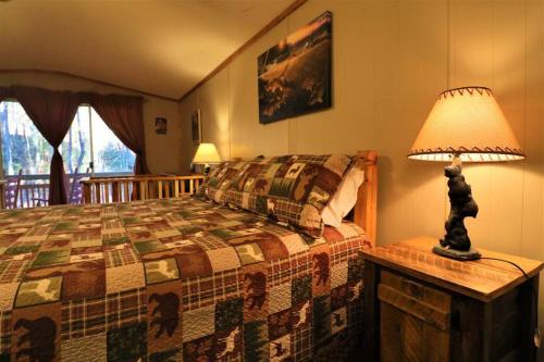 a bedroom with a bed with a lamp on a table at Cute Cabin creek & Firepit #12 in Helen