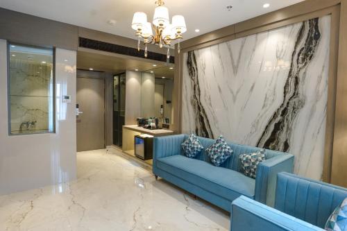a living room with a blue couch and a marble wall at InstaFeel Hotel in Navi Mumbai