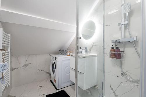 a white bathroom with a washing machine and a shower at Logement 7 personnes près de Disney & Paris in Chanteloup-en-Brie