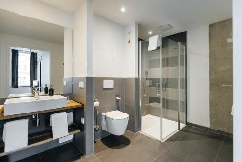 a bathroom with a sink and a toilet and a shower at Felix Suiten am Augustusplatz in Leipzig