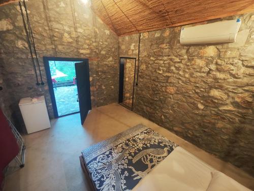 Cette chambre est dotée d'un mur en pierre et d'un lit. dans l'établissement Togo iztuzu Stonehouse-4, à Boğazağzı