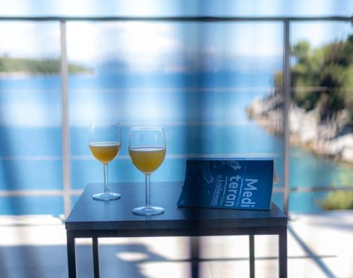 two glasses of wine sitting on a table at Mljet 4You - Beach House in Sobra