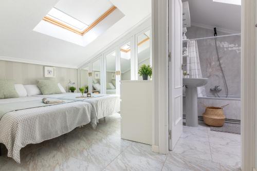 ein weißes Schlafzimmer mit einem Bett und einem Badezimmer in der Unterkunft Apartamento Ría de Mogro in Mogro