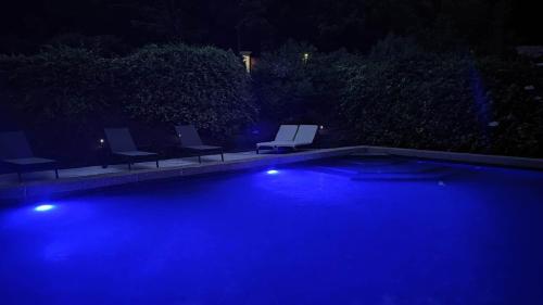 - une piscine avec des chaises et des lumières la nuit dans l'établissement L'Escapade Amoureuse Ardéchoise, à Jaujac