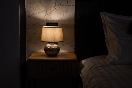 a lamp on a night stand next to a bed at MooDee Suite - Piata Sfatului in Braşov