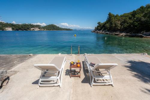 een paar stoelen en een tafel op het strand bij Mljet 4You - Beach House in Sobra