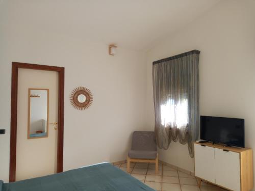 sypialnia z łóżkiem, telewizorem i krzesłem w obiekcie Villa Acquamarina w mieście Calasetta