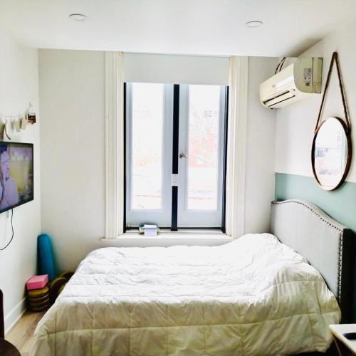 een slaapkamer met een bed en een raam bij La maisonnette in Montreal
