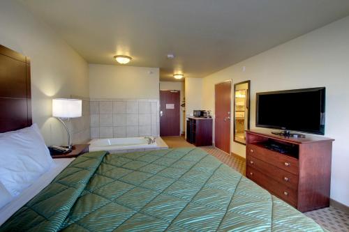 1 dormitorio con 1 cama grande y TV de pantalla plana en Cobblestone Inn & Suites - Harper, en Harper