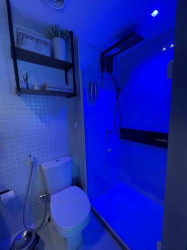 y baño azul con aseo y ducha. en LINDO FLAT NO FAROL DA BARRA, en Salvador