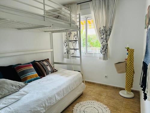 1 dormitorio con cama blanca y ventana en Apartamento 100m2 con piscina y jardín para 6 personas en Cambrils, en Cambrils