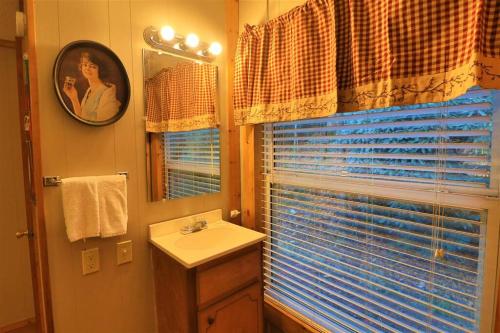 ein Bad mit einem Waschbecken, einem Spiegel und einem Fenster in der Unterkunft Mountain Cabin in woods 3 minutes to Helen #13 in Helen