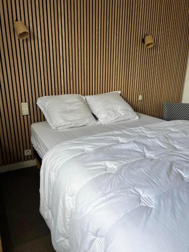 um quarto com uma cama com lençóis brancos e almofadas em Appartement confortable et lumineux 60m² em Pluneret