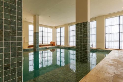 聖薩爾瓦多德胡胡伊的住宿－胡胡伊豪生大酒店，一个带绿色瓷砖墙壁和窗户的大型游泳池