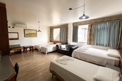 een hotelkamer met 3 bedden en een bank bij Hotel Golden Star in Curitiba