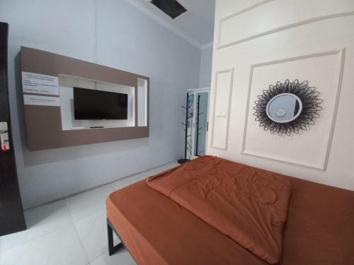 a bedroom with a bed and a flat screen tv at OYO 93962 Jm Guest House in Pundong