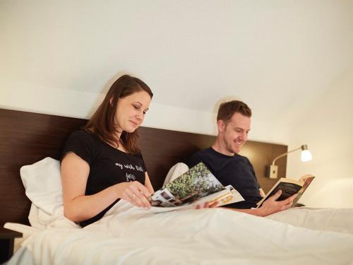 a man and woman sitting in bed reading books at Comfy farmhouse villa in Limburg in Roggel