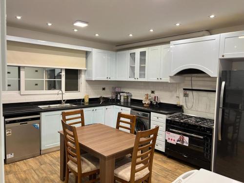 a kitchen with white cabinets and a wooden table with chairs at Elkarma 4 in Sheikh Zayed