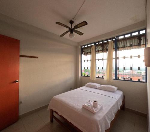 1 dormitorio con 1 cama con 2 toallas y ventilador en Hospedaje Koral en Tarapoto