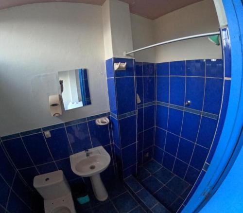 Baño de azulejos azules con aseo y lavamanos en Hospedaje Koral en Tarapoto