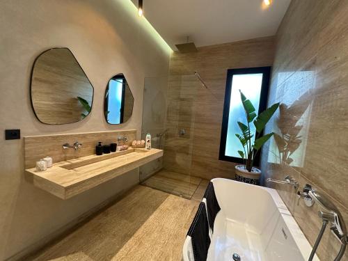 マラケシュにあるVilla Hicham Golf Marrakechの浴槽、洗面台、鏡のあるバスルーム