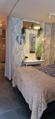 een slaapkamer met een bed en een tafel met planten bij Noorderster aan zee in Zandvoort