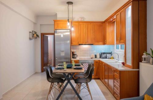 una cocina con armarios de madera y una mesa pequeña con sillas. en Cloe Corfu Airport Apartment en Anemómylos