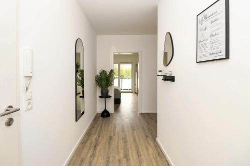 a hallway with white walls and wooden floors at LIGHTPLACE - Moderne Apartments in Braunschweig - Balkon - Netflix - Am Kanal in Braunschweig