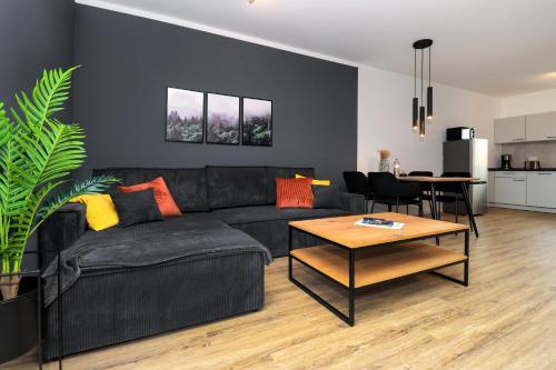 a living room with a black couch and a table at LIGHTPLACE - Moderne Apartments in Braunschweig - Balkon - Netflix - Am Kanal in Braunschweig